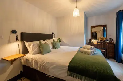 a bedroom with a large bed with green pillows at Royal Oak Pub in Cartmel