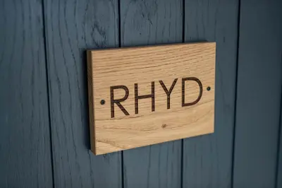 a wooden sign that reads hybrid hanging on a wooden wall at Royal Oak Pub in Cartmel