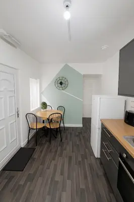 a kitchen with a table and chairs and a clock on the wall at 4-Bedroom House sleeps 9 in Liverpool Perfect for Contractors - Free Parking - Fast WiFi - Fully Equipped Kitchen - Hosted by By Hinkley Homes Short Lets & Serviced Accommodation in Liverpool