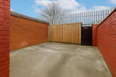 a garage with a wooden gate and a red brick wall at 4-Bedroom House sleeps 9 in Liverpool Perfect for Contractors - Free Parking - Fast WiFi - Fully Equipped Kitchen - Hosted by By Hinkley Homes Short Lets & Serviced Accommodation in Liverpool