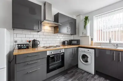 a kitchen with gray cabinets and a washer and dryer at 4-Bedroom House sleeps 9 in Liverpool Perfect for Contractors - Free Parking - Fast WiFi - Fully Equipped Kitchen - Hosted by By Hinkley Homes Short Lets & Serviced Accommodation in Liverpool