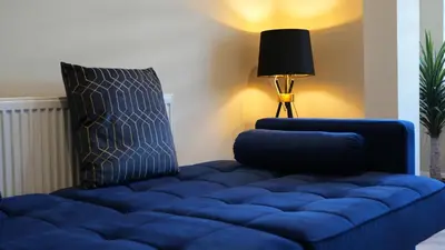 a blue couch in a living room with a lamp at Five Apartments in Blackpool