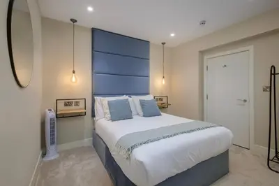 a bedroom with a large bed with a blue headboard at Five Apartments in Blackpool
