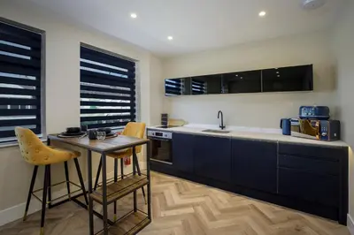a kitchen with black cabinets and a table and a sink at Five Apartments in Blackpool