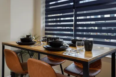 a table with chairs and plates and wine glasses at Five Apartments in Blackpool