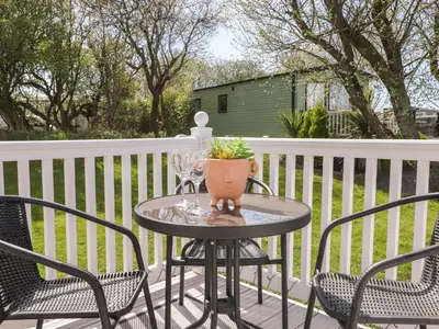 a table with two chairs and a vase on a porch at The Maples in Millom