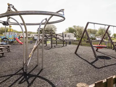 a row of empty swings at a playground at The Maples in Millom