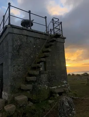 a stone building with a staircase with a sunset in the background at SANDYVIEWS in Grange Over Sands