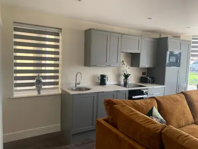 a living room with a couch and a kitchen at Willshaw Suites for families over 25 only in Blackpool
