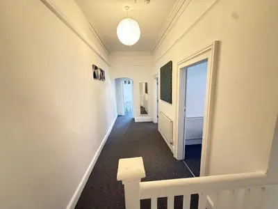 a hallway with white walls and a staircase with a door at Deco apartment 5 min walk from Blackpool tower sleeps 12 in Blackpool