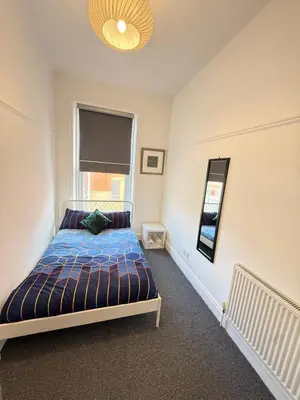a bedroom with a bed with a blue comforter and a window at Deco apartment 5 min walk from Blackpool tower sleeps 12 in Blackpool