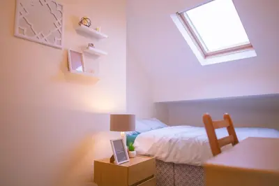 a bedroom with a bed and a table with a lamp at Anfield Apartment in Liverpool