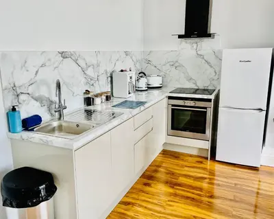 a white kitchen with a sink and a refrigerator at Beach Sunset in Lytham St Annes