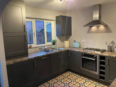 a kitchen with gray cabinets and a stove top oven at Tranquil 3 bedroom town house with Sky Glass in Thornton