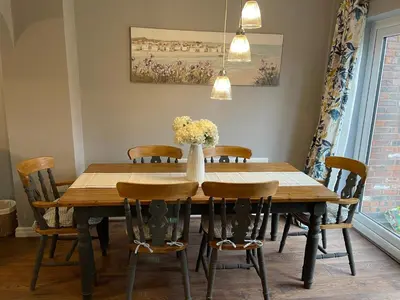 a dining room table with chairs and a vase of flowers at Tranquil 3 bedroom town house with Sky Glass in Thornton