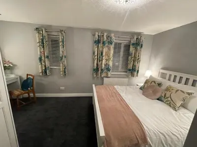 a bedroom with a bed and two windows at Tranquil 3 bedroom town house with Sky Glass in Thornton