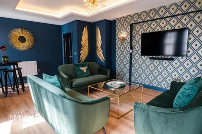 a living room with blue walls and chairs and a tv at The Old Bank Apartments in Blackpool