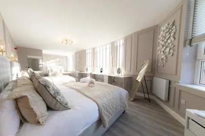 a white bedroom with two beds and a desk at The Old Bank Apartments in Blackpool
