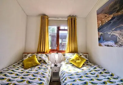 a bedroom with two beds with yellow pillows and a window at Dot's Place 1 in Carnforth