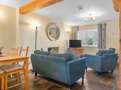a living room with two blue chairs and a table at Beautiful 3 Bed Cottage in the Heart of Flookburgh - Pass the Keys in Grange Over Sands
