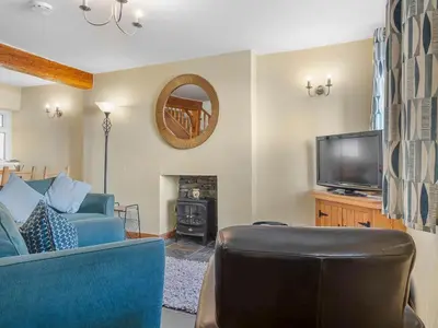 a living room with a blue couch and a television at Beautiful 3 Bed Cottage in the Heart of Flookburgh - Pass the Keys in Grange Over Sands