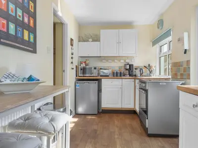 a kitchen with white cabinets and stainless steel appliances at Beautiful 3 Bed Cottage in the Heart of Flookburgh - Pass the Keys in Grange Over Sands