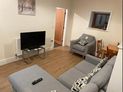 a living room with a couch and a television at Salcombe Holiday Cottage in Wilpshire