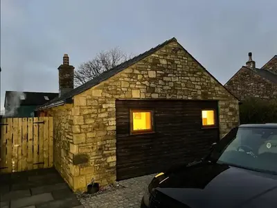 a stone house with a garage with two windows at Salcombe Holiday Cottage in Wilpshire
