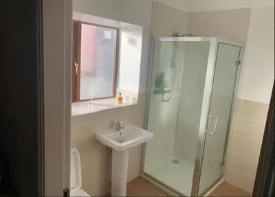 a bathroom with a sink and a glass shower at Salcombe Holiday Cottage in Wilpshire