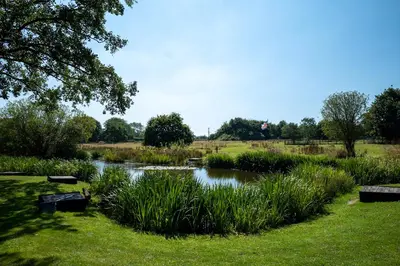 a pond in the middle of a grass field at Abbey Farm House Ormskirk in Ormskirk