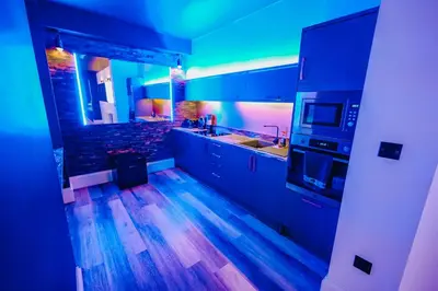 a kitchen with blue lighting and a wooden floor at BREEZE BLACKPOOL LUXURY SUITES in Blackpool