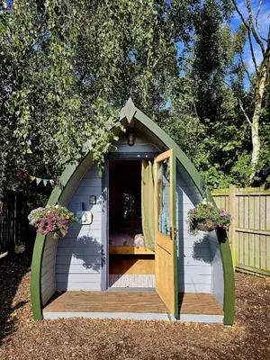 a small shed with a door in a yard at The Forest Pod - Wood Fired Hot Tub and Fire Pit in Hambleton
