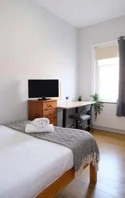 a bedroom with a bed and a desk with a television at Seymour Townhouse by Serviced Living Liverpool in Liverpool