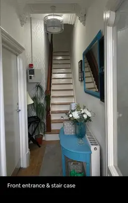 a hallway with stairs and a vase of flowers on a table at 1 bedroom spacious apartment in Lytham St Annes