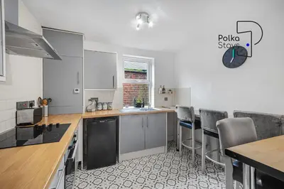 a kitchen with a table and chairs and a clock on the wall at PolkaDot Winter Gardens - Large Modern Apartments in Blackpool by PolkaStays in Blackpool