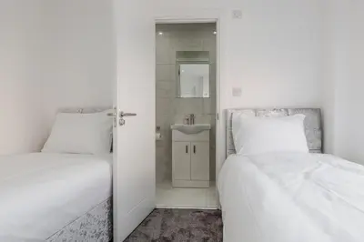 a bedroom with two beds and a bathroom with a sink at RST Luxury Aparthotel in Liverpool