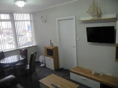 a living room with a table and a television on a wall at Mermaid Holiday Flats in Blackpool