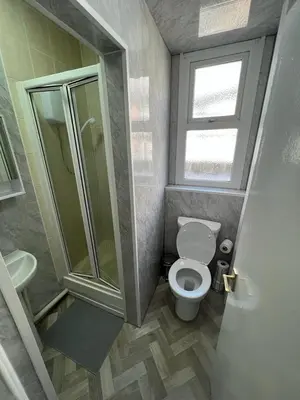 a small bathroom with a toilet and a shower at Mermaid Holiday Flats in Blackpool