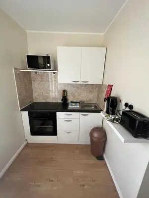 a small kitchen with white cabinets and a microwave at Mermaid Holiday Flats in Blackpool