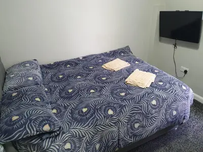 a bed with a blue comforter with two sheets at Mermaid Holiday Flats in Blackpool