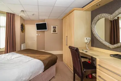 a bedroom with a bed and a desk with a mirror at Cherry Tree House in Blackpool