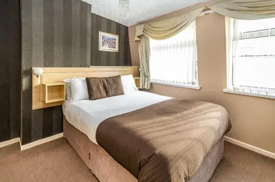 a bedroom with a bed and two windows at Cherry Tree House in Blackpool