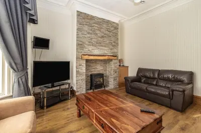 a living room with a leather couch and a fireplace at Cherry Tree House in Blackpool