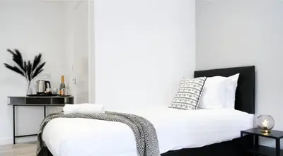 a white bed with a black headboard and white pillows at The Kop End Hotel by Serviced Living Liverpool in Liverpool