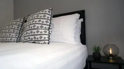 a white bed with pillows and a lamp on a table at The Kop End Hotel by Serviced Living Liverpool in Liverpool