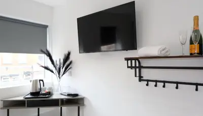 a living room with a table and a tv on a wall at The Kop End Hotel by Serviced Living Liverpool in Liverpool