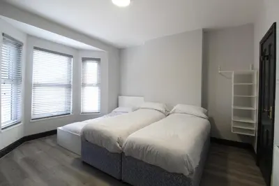 a bedroom with two beds and two windows at Anfield house in Liverpool
