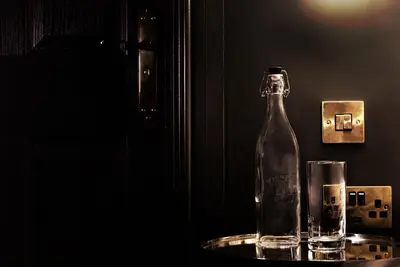 a glass bottle on a table next to a glass at Swan & Railway Hotel Wigan in Wigan