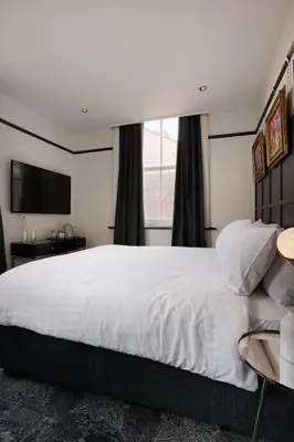 a bedroom with a large white bed and a window at Swan & Railway Hotel Wigan in Wigan