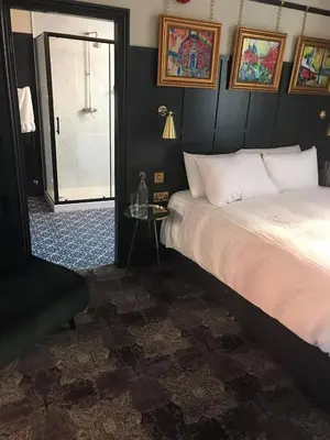 a bedroom with a bed and a table and a door at Swan & Railway Hotel Wigan in Wigan